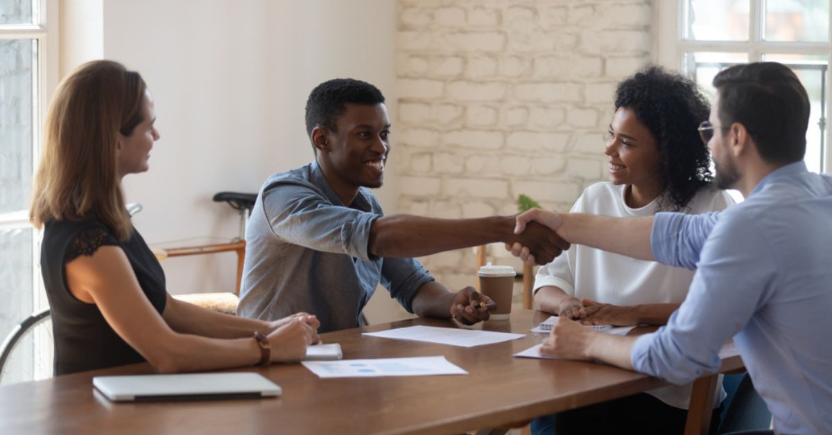 Happy man in a conference room shaking hands across the table