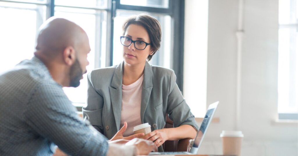 Man and woman talking in front of a laptop