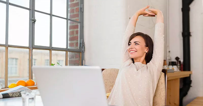 Women at a desk stretching her hands over her head