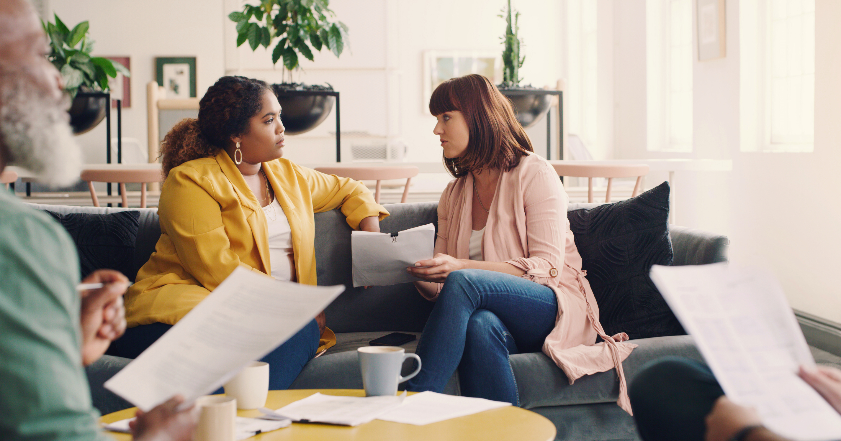 Two people sitting on a couch in an office setting.